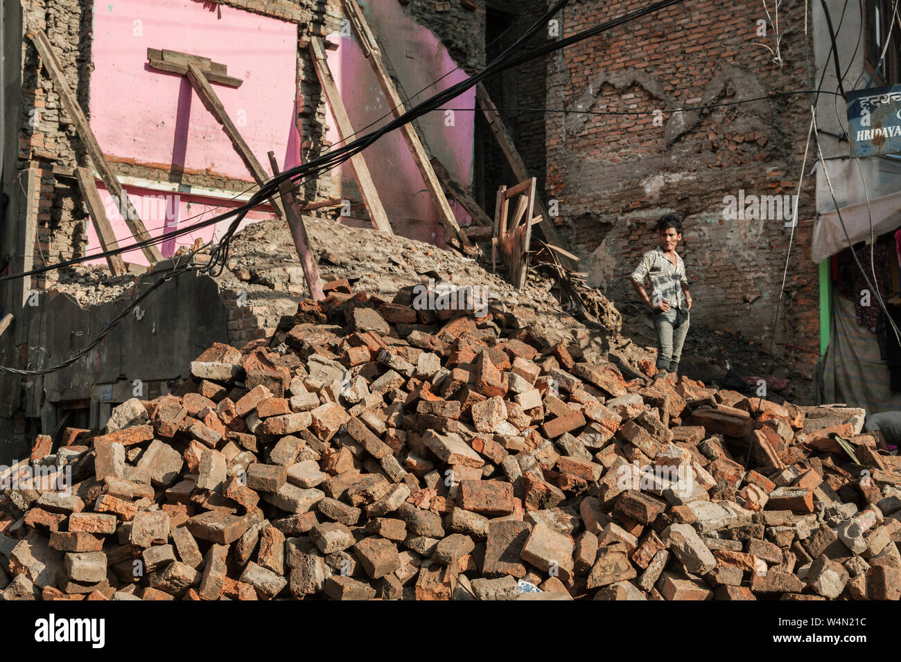 Mann stand auf einem Haufen Steine aus einem eingestürzten Haus nach einem Erdbeben in Kathmandu, Nepal Stockfoto