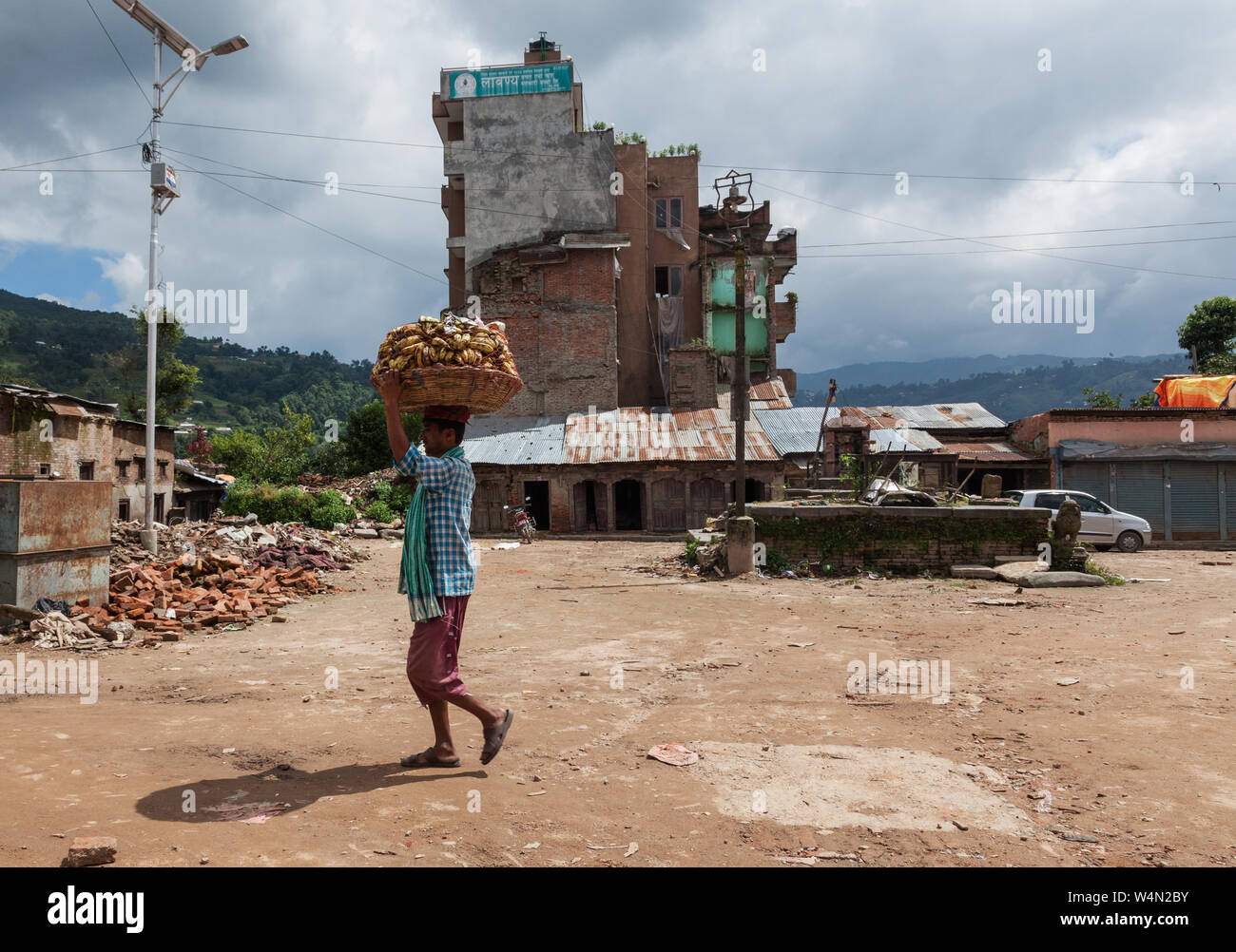 Mann, der einen Korb von Bananen auf seinem Kopf im Dorf Sankhu in Nepal nach dem Erdbeben von 2015. Stockfoto