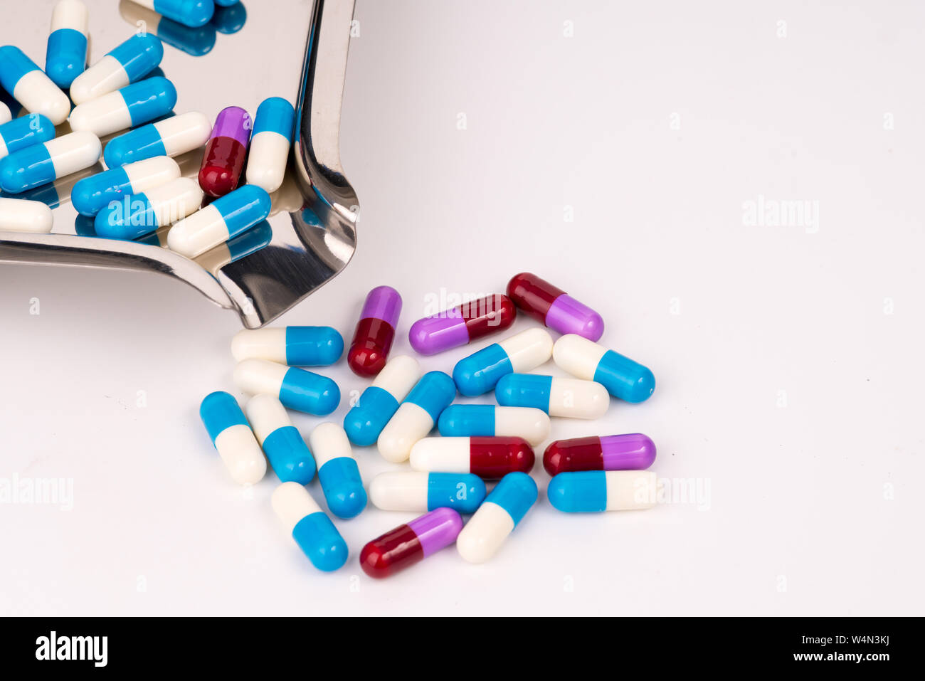 Bunte Antibiotikum Kapseln auf Edelstahl Droge Fach und Fallen auf weißem Hintergrund Stockfoto