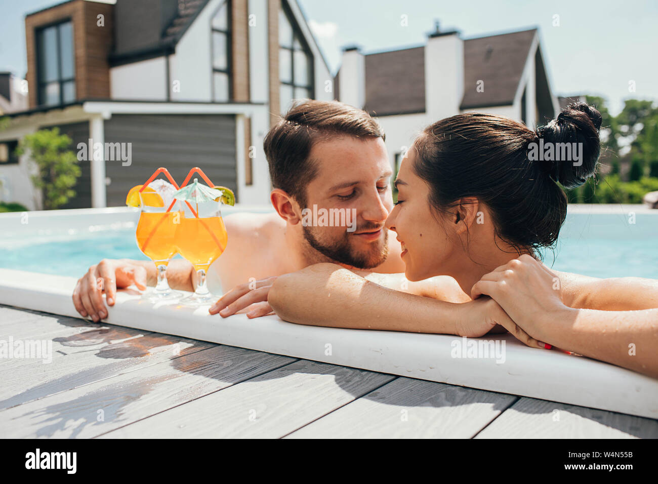 Mann und eine Frau schauen liebevoll einander an, während in den Pool. Auf Wiedersehen, hi Sommer Urlaub - Schwimmen und Bräunen Stockfoto