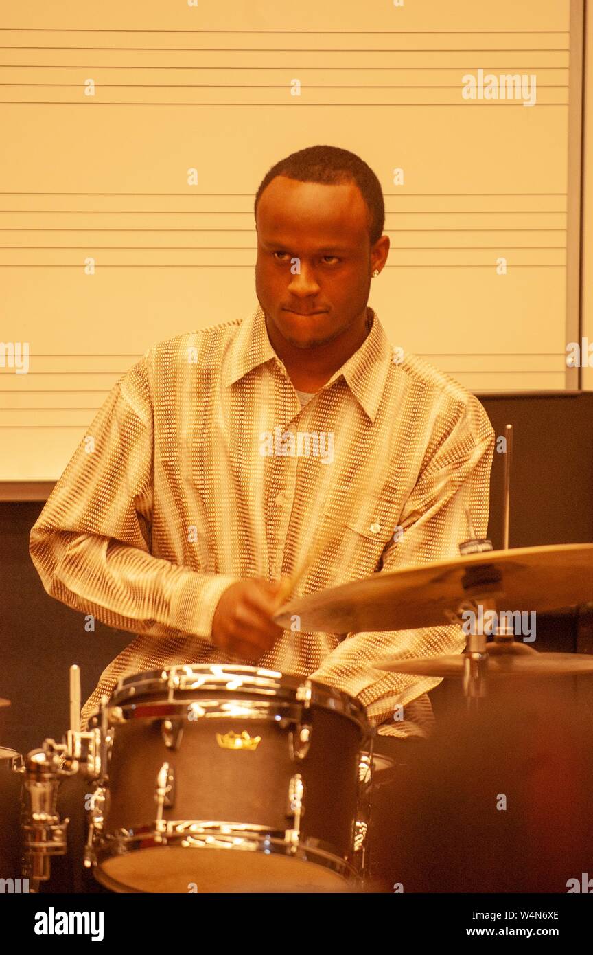 Mittellange Aufnahme eines Musikers, mit Blick auf die Kamera, während Schlagzeug zu spielen, bei einer Veranstaltung mit Black History Month an der Johns Hopkins Universität, Baltimore, Maryland, 26. Februar 2006. Vom Homewood Sammlung Fotografie. () Stockfoto