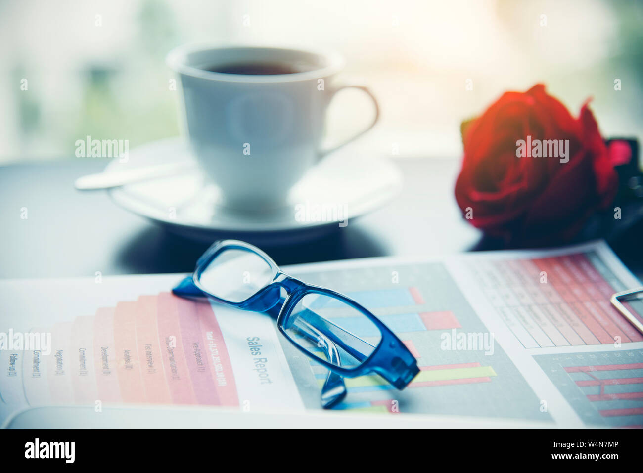 Business Material, Graphen, Diagramme, Rechner, Brille, Stift und eine Tasse Kaffee im Büro. Blick auf die Stadt ist ein Hintergrund. Stockfoto