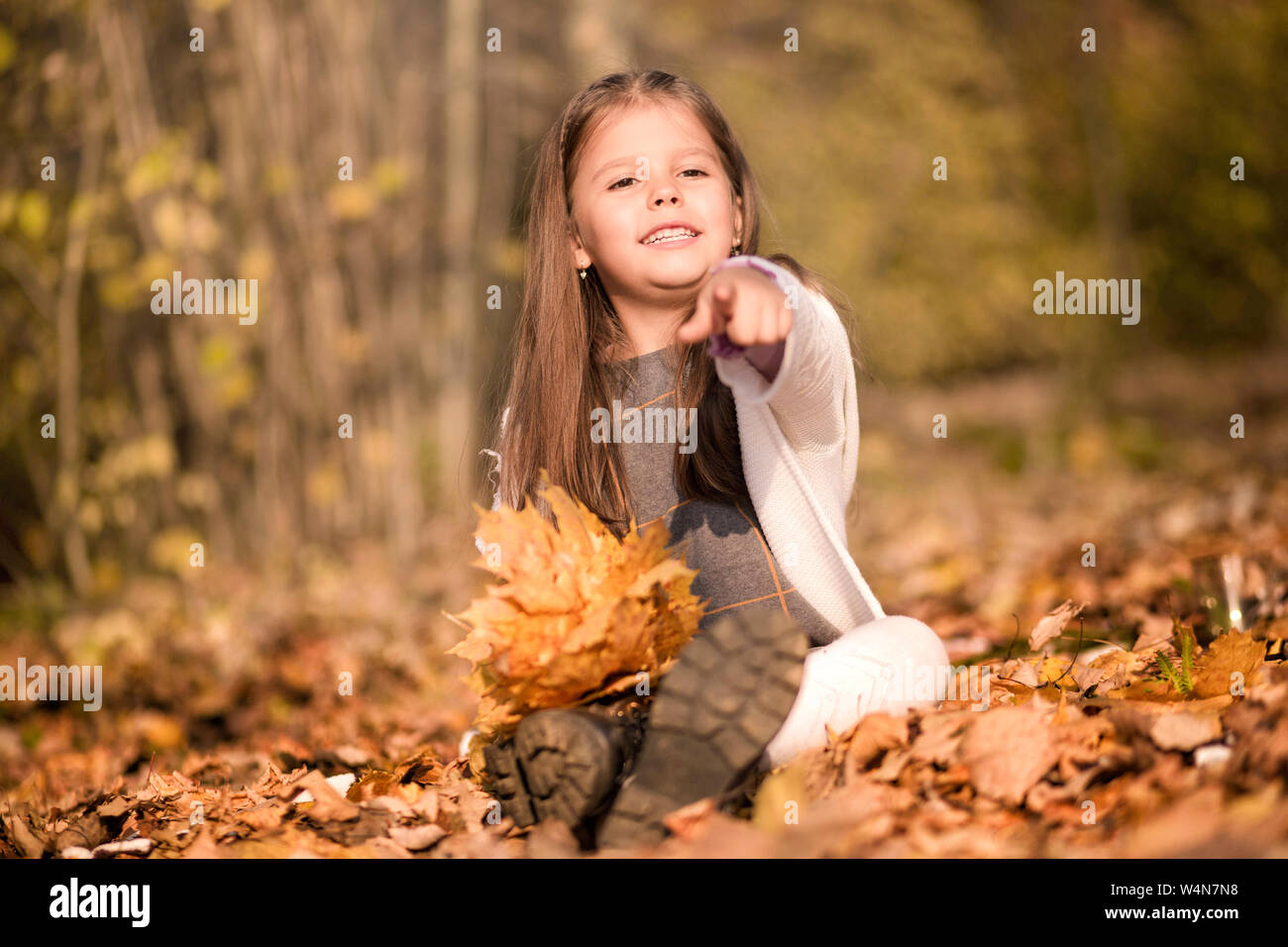 Foto von kleinen Mädchen in den Wald zu sitzen mit einem Blumenstrauß Herbst gelbe Blätter Stockfoto