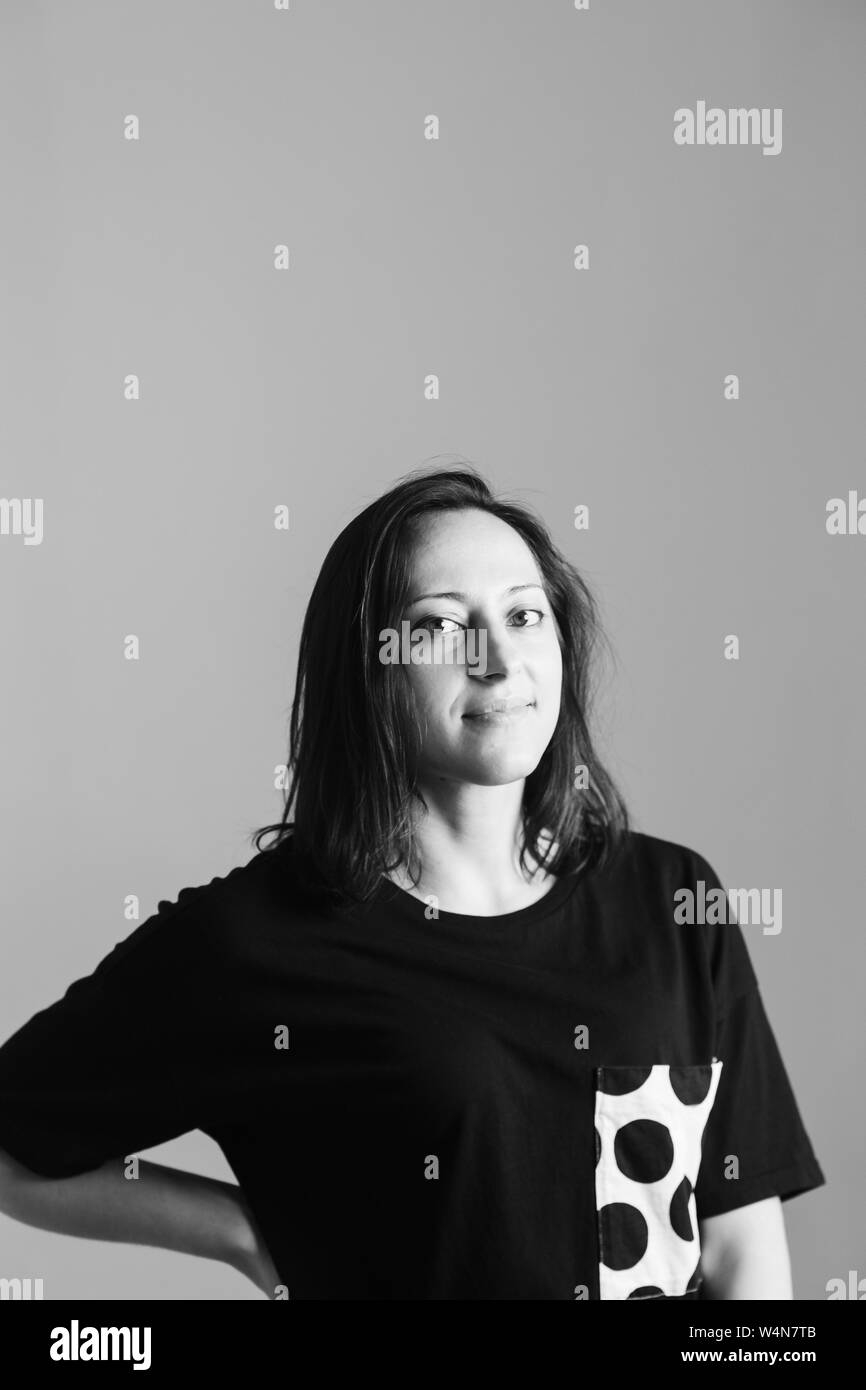 Schwarze und weiße Studio Portrait einer attraktiven Frau in einem schwarzen T-Shirt gegen einfachen Hintergrund Stockfoto