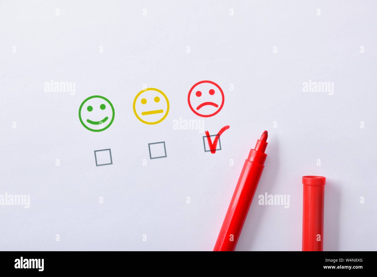 Negative Zufriedenheit mit roten Marker Stift markiert mit farbigen Emoticons auf weißem Papier vertreten. Horizontale Komposition. Ansicht von oben. Stockfoto