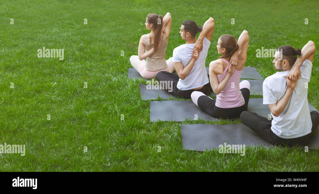 Freunde machen Yoga Übungen mit den Händen hinter dem Rücken festgehakt Stockfoto