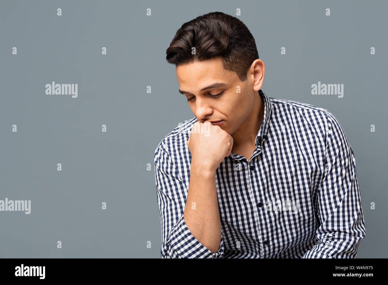 Nachdenklich stattlicher Mann mit kariertem Hemd auf grauem Hintergrund Stockfoto