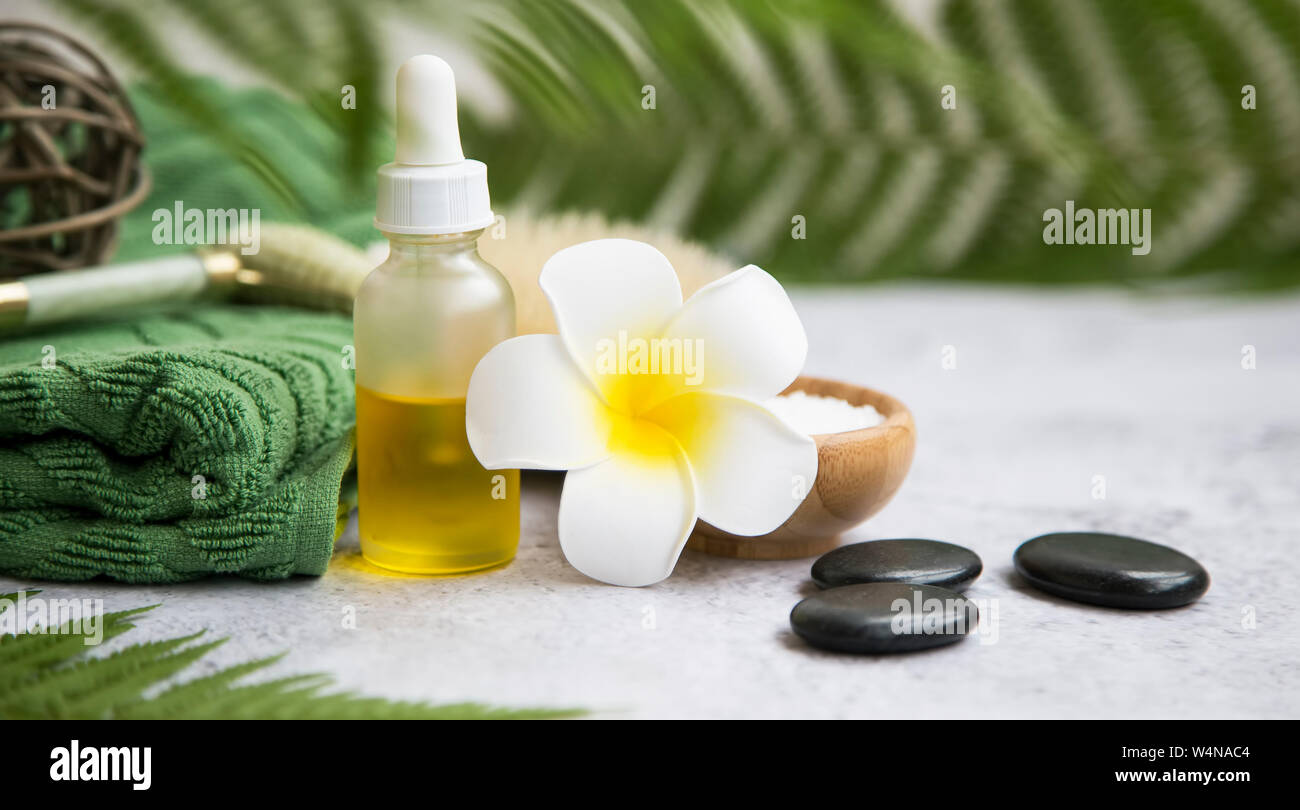 Spa Noch leben Einstellung mit tropischen frangipani Blume, Badesalz und Ölflasche, Massage Steine, grün Handtuch, tropischen botanischen Green Spa, natürliche Stockfoto