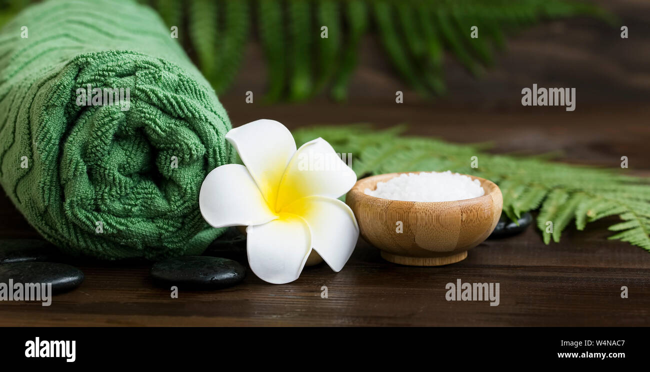 Spa Noch leben Einstellung mit tropischen frangipani Blume, Massage Steine und grünen Handtuch, tropischen botanischen Green Spa, natürliche wellness Hintergrund Stockfoto