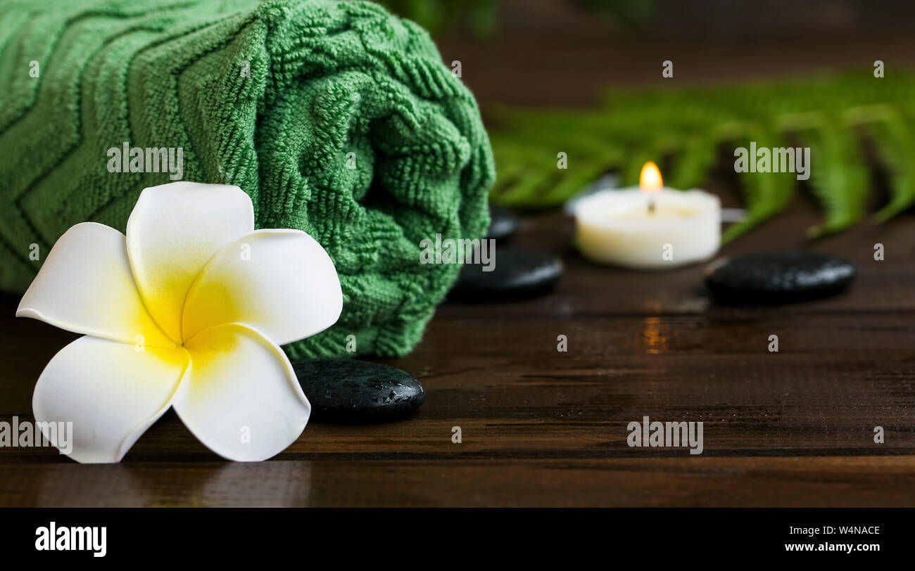 Spa Noch leben Einstellung mit tropischen frangipani Blume, Massage Steine, Kerze und grün Handtuch, tropischen botanischen Green Spa, natürliche Wellness hinterg Stockfoto