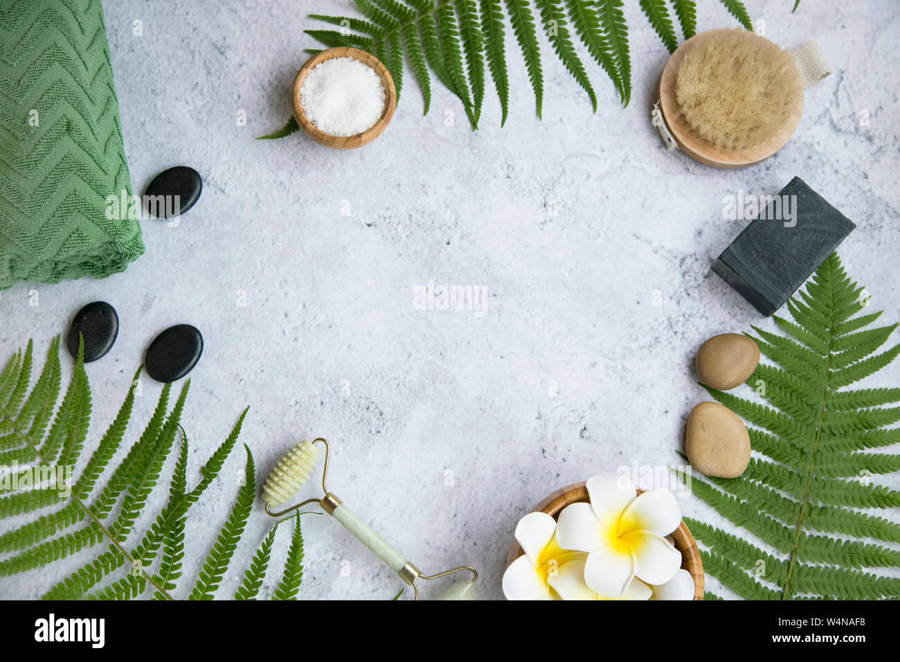 Grüne botanischen Spa flatlay mit Farn, Holzkohle, Seife, Massage Steine, frangipani Blüten und Badesalz, Spa still life-Einstellung mit Kopie Raum Stockfoto
