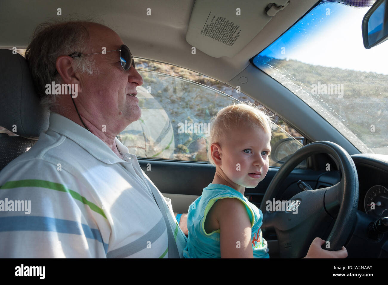 Junge Auto auf großväter Lap Stockfoto