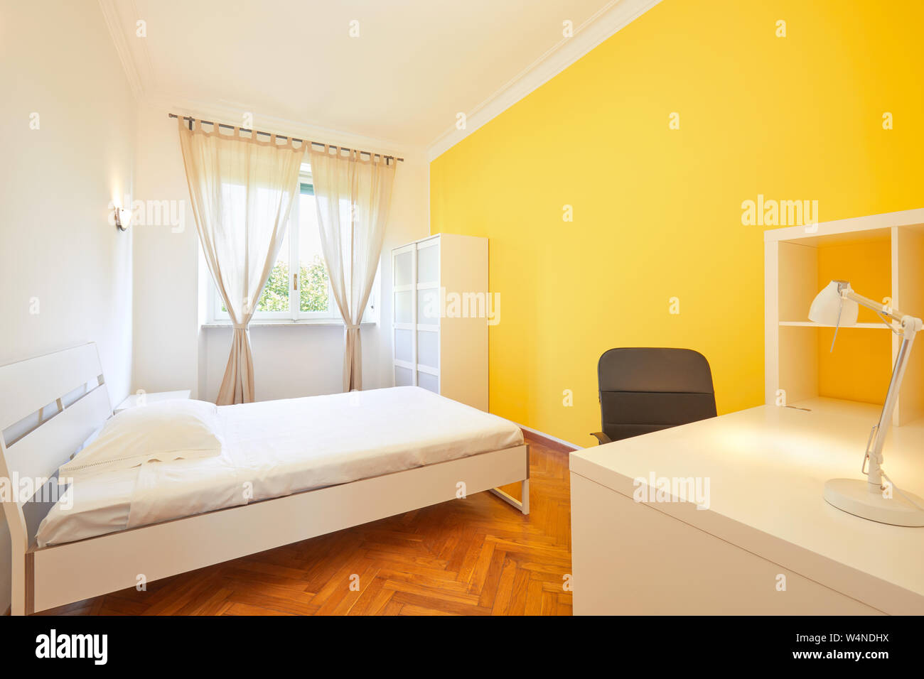 Schlafzimmer zum Mieten in renovierte Apartment mit gelben Wänden und weißen Schreibtisch Stockfoto