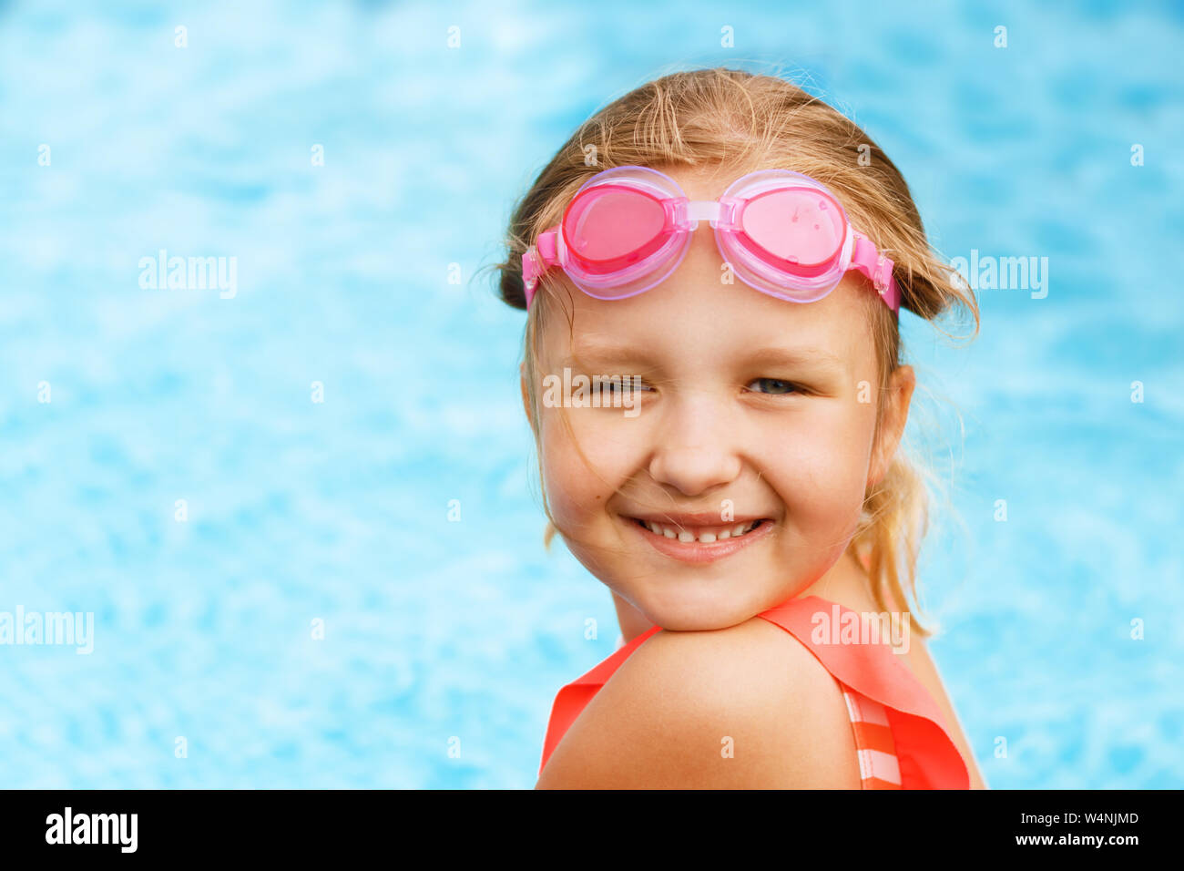 Charmantes kleines Mädchen, schwimmt im Pool. Ein Kind mit einer Brille lächelt und sieht in die Kamera. Stockfoto