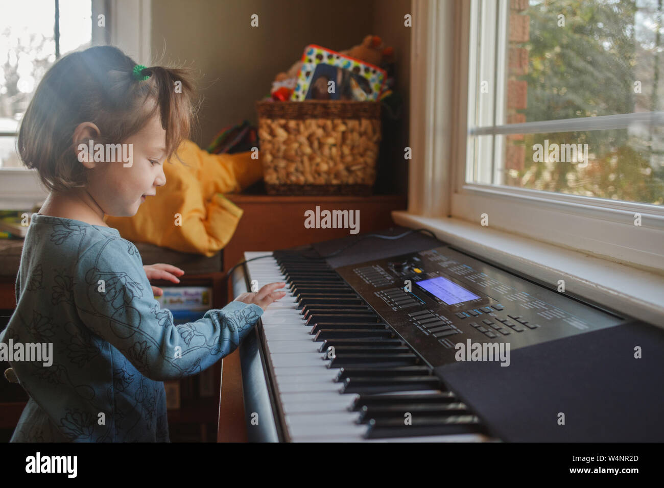 Porträt eines niedlichen kleinen Kind Klavier spielen vor einem Fenster Stockfoto