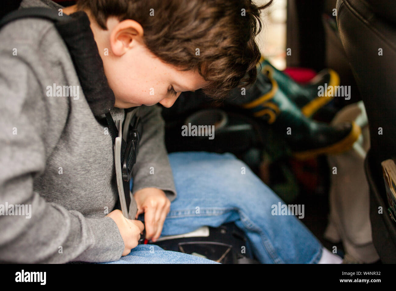 Ein kleines Kind arbeitet fleißig, um sich in eigenen Kindersitz anschnallen Stockfoto