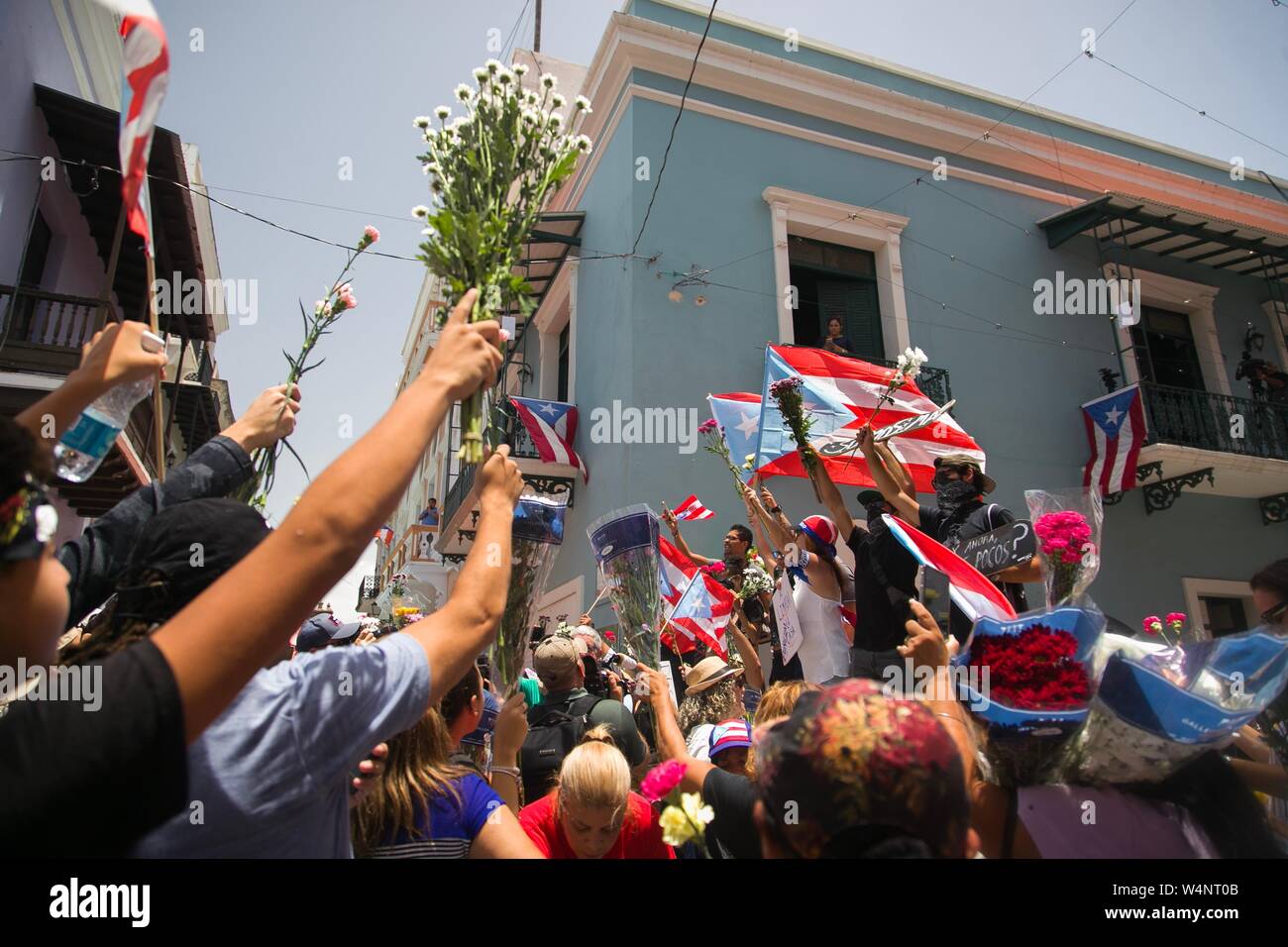 San Juan, Puerto Rico. 24. Juli, 2019. Demonstranten protestieren mit Puerto Rican Fahnen und Blumen vor der Residenz des Gouverneurs Rossello, auch bekannt als La Fortaleza. Die Proteste von einem Korruptionsskandal in der Regierung und die Veröffentlichung von Nachrichten in einer Chat Group, in denen ausgelöst wurden, entsprechend viele, einige Bemerkungen waren feindselig gegenüber Frauen und Homosexuellen und respektlos der zahlreichen Opfer des Hurrikan Maria von 2017. Puerto Rico's Kopf der Regierung, Rossello, ist immer noch im Amt, im Gegensatz zu den anhaltenden Spekulationen über seinen Rücktritt. Credit: Marcos Caballero/dpa/Alamy leben Nachrichten Stockfoto