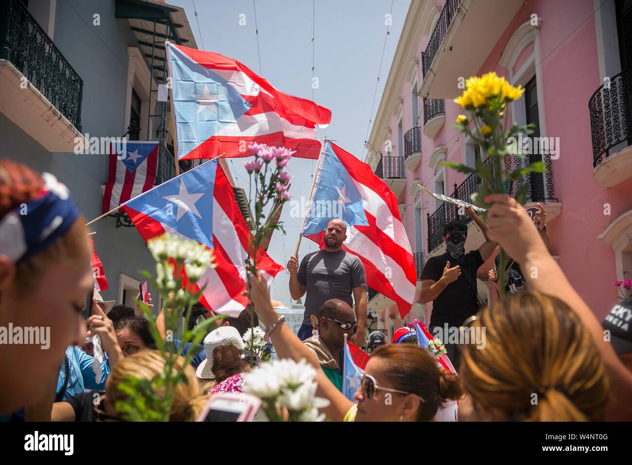 San Juan, Puerto Rico. 24. Juli, 2019. Demonstranten protestieren mit Puerto Rican Fahnen und Blumen vor der Residenz des Gouverneurs Rossello, auch bekannt als La Fortaleza. Die Proteste von einem Korruptionsskandal in der Regierung und die Veröffentlichung von Nachrichten in einer Chat Group, in denen ausgelöst wurden, entsprechend viele, einige Bemerkungen waren feindselig gegenüber Frauen und Homosexuellen und respektlos der zahlreichen Opfer des Hurrikan Maria von 2017. Puerto Rico's Kopf der Regierung, Rossello, ist immer noch im Amt, im Gegensatz zu den anhaltenden Spekulationen über seinen Rücktritt. Credit: Marcos Caballero/dpa/Alamy leben Nachrichten Stockfoto