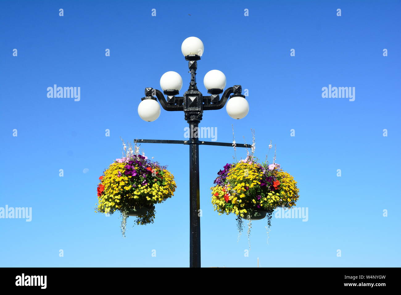 Classic Victorian Lamp Post mit hängenden Blumenkörben Stockfoto