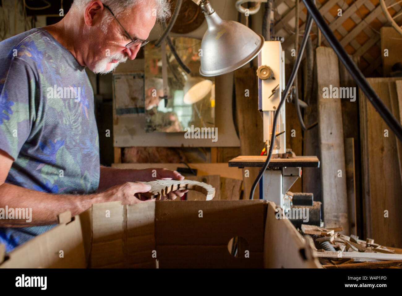 Seitliche Sicht auf einen älteren Mann Inspektion Handarbeit in der Werkstatt Stockfoto