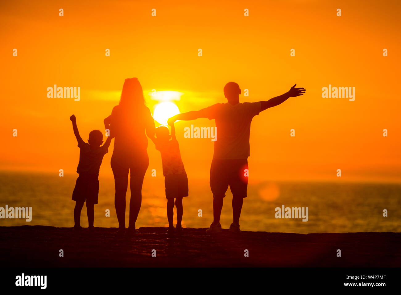 Perfekte Familie beobachten Sie den Sonnenuntergang über dem Meer Stockfoto