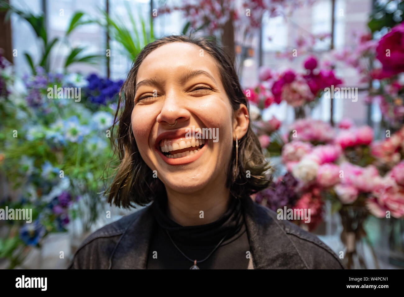Lächelnde junge Frau im Blumenladen in Amsterdam und Kauf von Blumen. Stockfoto