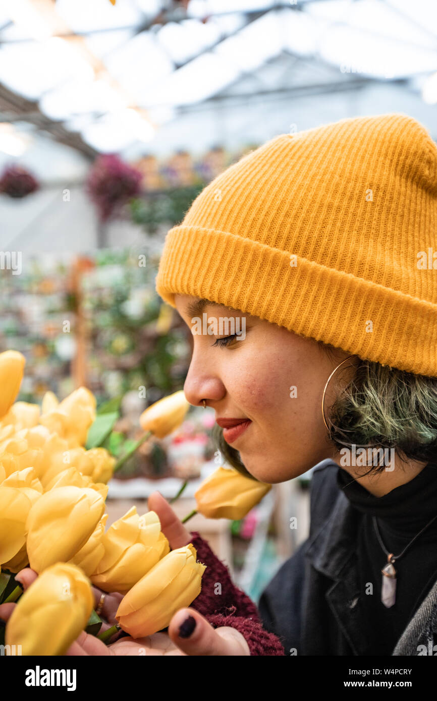 Junge Frau berühren gelbe Tulpen im Blumengeschäft. Kauf von Blumen. Stockfoto