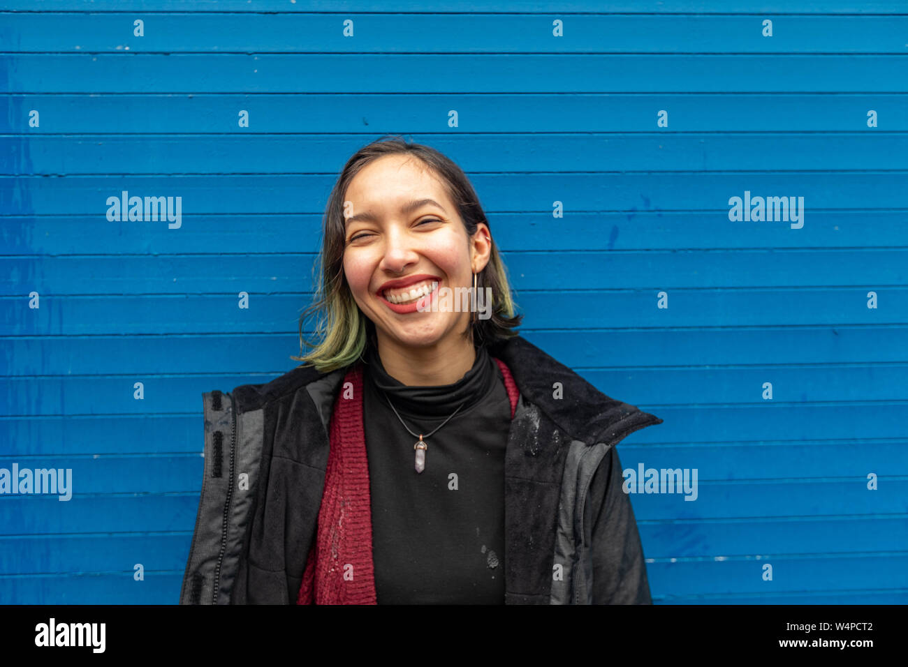 Glückliche Frau stehen im Regen auf der Straße, in der Nähe der blauen Wand. Stockfoto