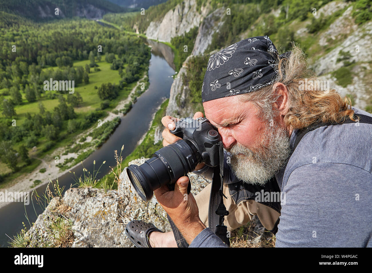 Landschaft Fotograf nimmt Bilder der Natur in einer felsigen Gegend, kletterte er auf die Spitze eines Berges oberhalb einer ruhigen Fluss. Stockfoto