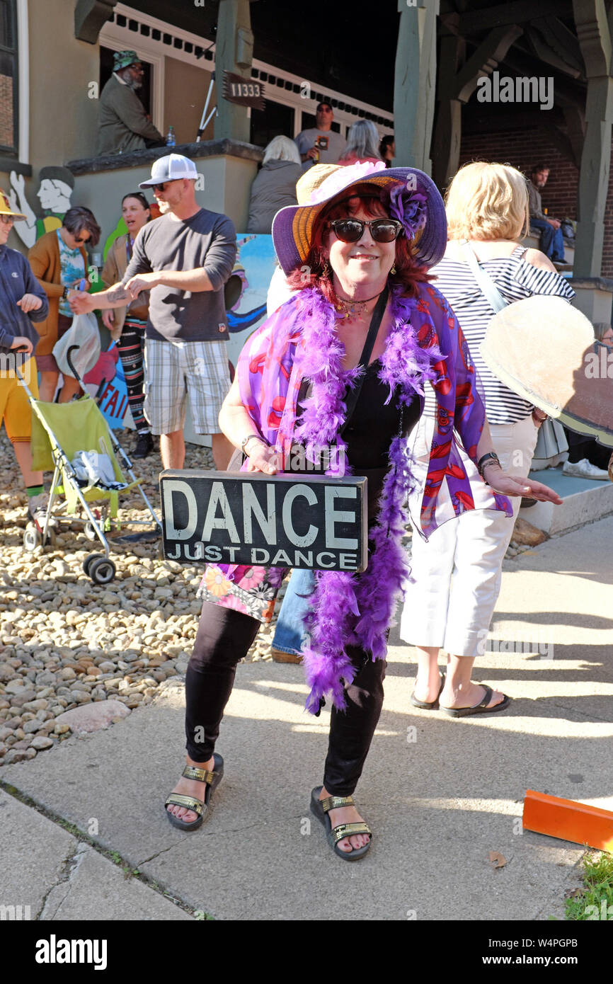Eine Frau tanzt im Freien mit einem Schild 'Dance Just Dance' auf der 50th Hessler Street Fair und der letzten Hessler Street Fair in Cleveland, Ohio, USA. Stockfoto