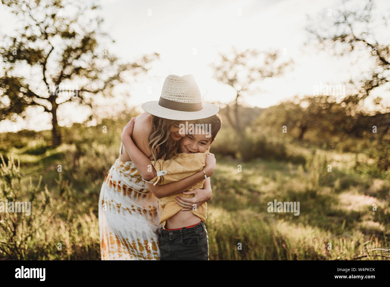 Junge Mutter umarmt der Sohn im sonnigen Wiese mit Hut auf Stockfoto