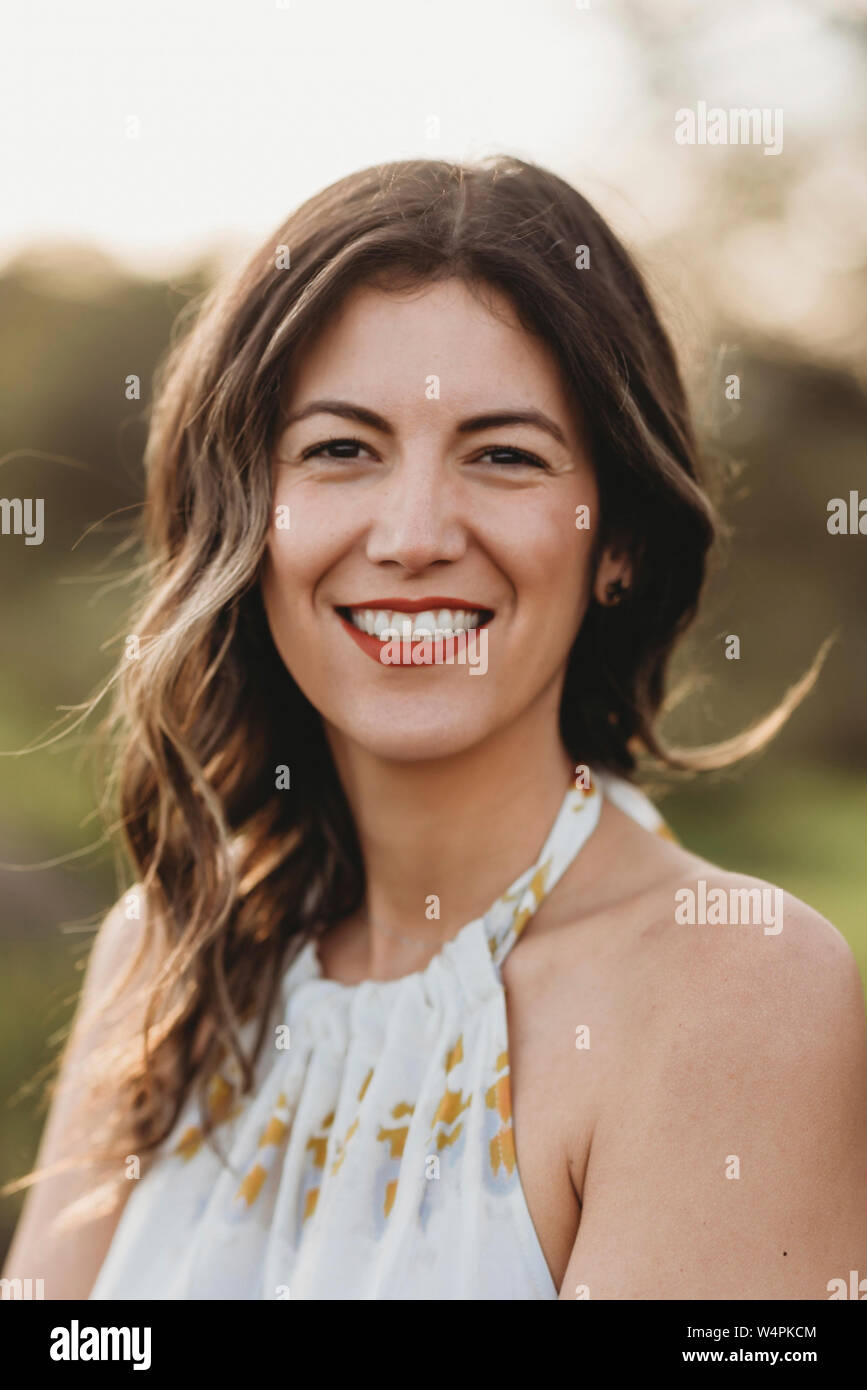 Headshot junge brünette Frauen lächelnd in Feld mit Hintergrundbeleuchtung Stockfoto