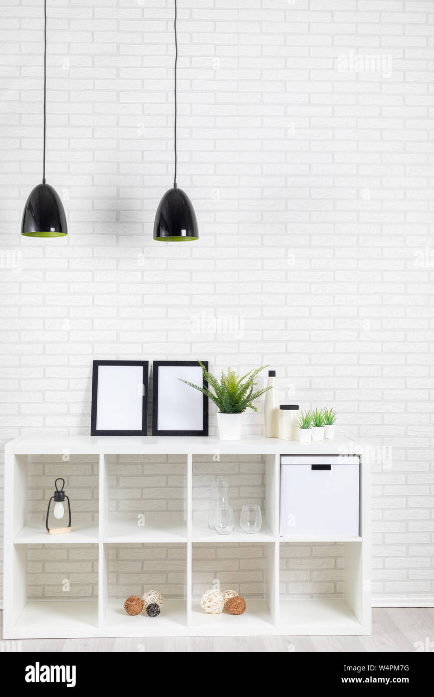 Moderne loft Einrichtung mit weißen Brickwall, Lampe, Regal, Bilder, Pflanzen und einige Deko/vertikaler Stockfoto