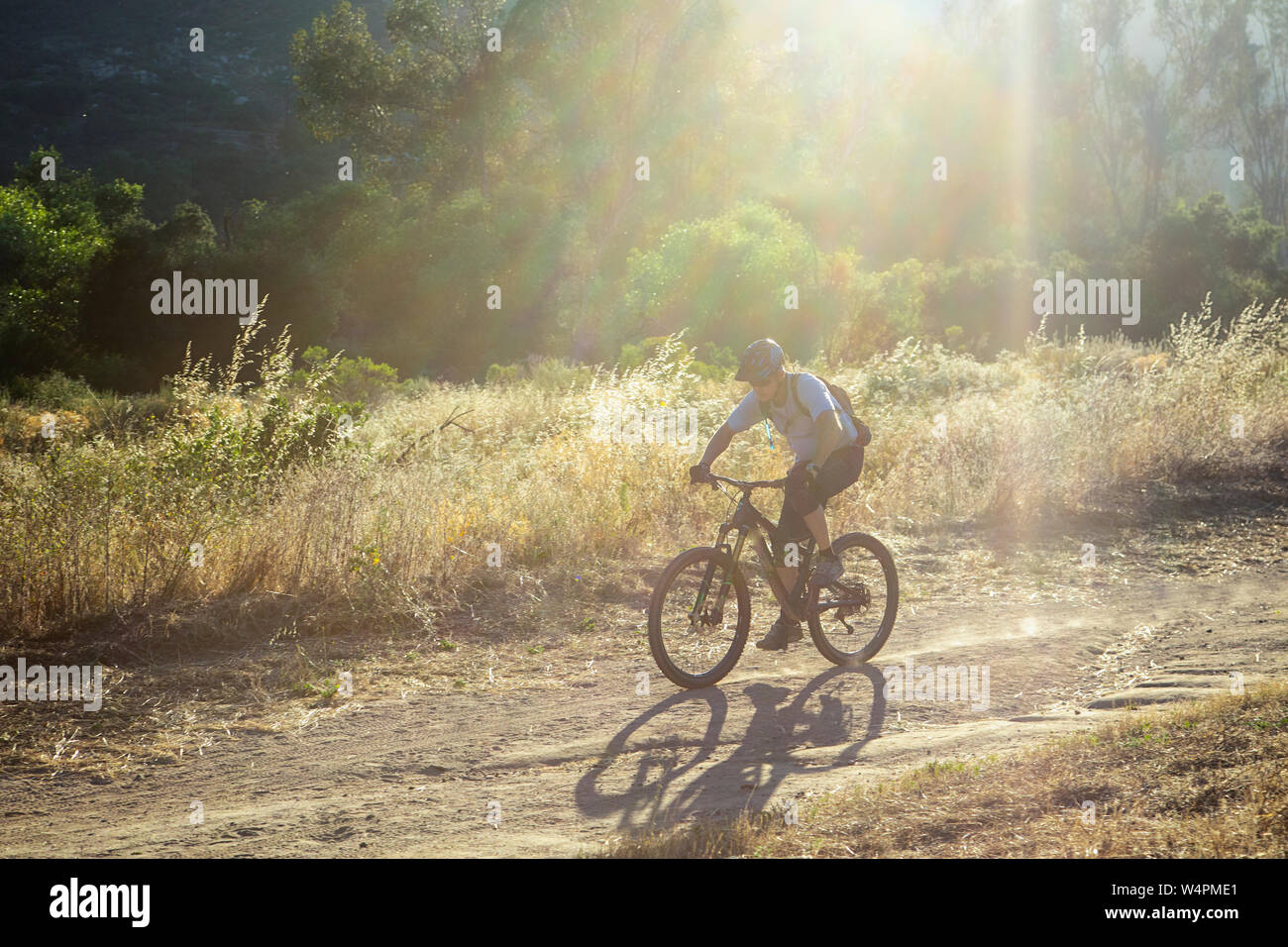 Reifer Mann reiten Mountainbike gegen helles Sonnenlicht auf Trail in CA Stockfoto