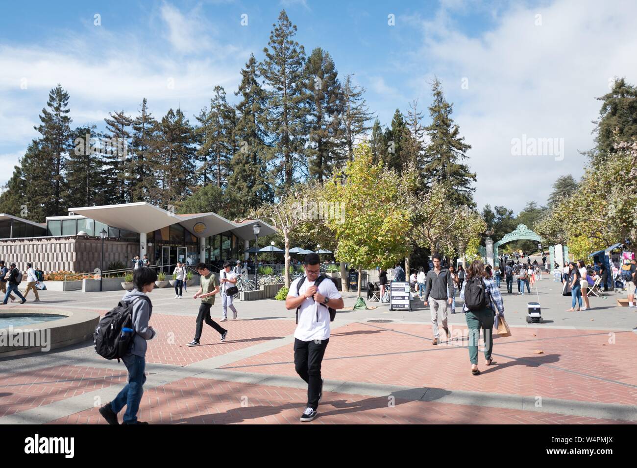 Große Massen von Studierenden Spaziergang durch den Campus der UC Berkeley in der Innenstadt von Berkeley, Kalifornien auf Sather Straße, mit einem Kiwi autonomen Lebensmittel-lieferservice Roboter auf der rechten Seite navigieren zwischen Fußgänger sichtbar, 9. Oktober 2018. () Stockfoto