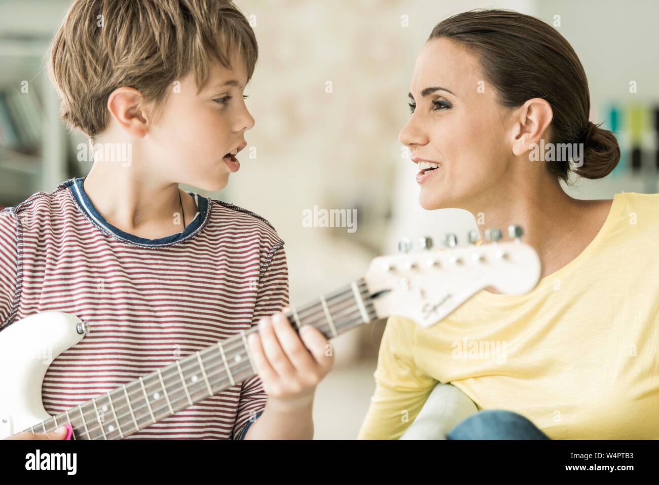 Mutter und Sohn gemeinsam Musik machen, beide singen und Sohn spielen, E-Gitarre, Nahaufnahme, Deutschland Stockfoto
