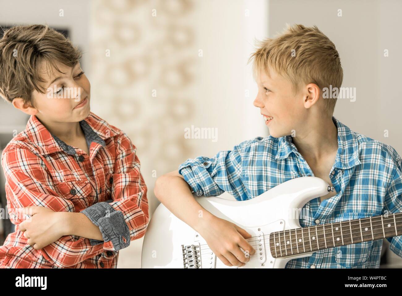 Zwei Jungen, Freunde, 10 Jahre alt, einer spielt E-Gitarre, lächelnd, Deutschland Stockfoto