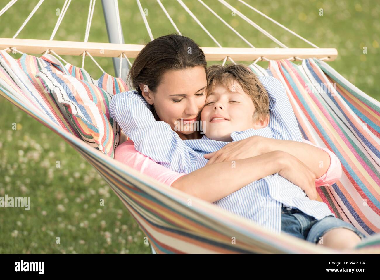 Mutter und Sohn liegen in Hängematten, kuscheln, die Augen geschlossen, Deutschland Stockfoto