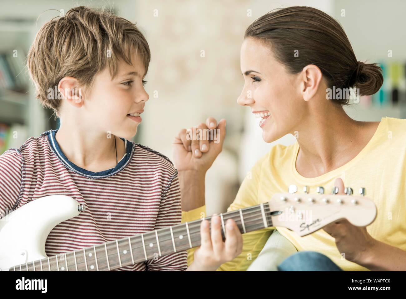 Mutter und Sohn gemeinsam Musik machen, beide singen und Sohn spielen Gitarre, Nahaufnahme, beide sich einander, Deutschland Stockfoto