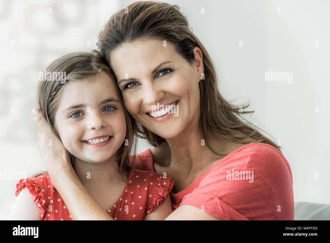 Mutter und Tochter sitzen zusammen auf der Couch und in die Kamera schauen, lächeln, Deutschland Stockfoto