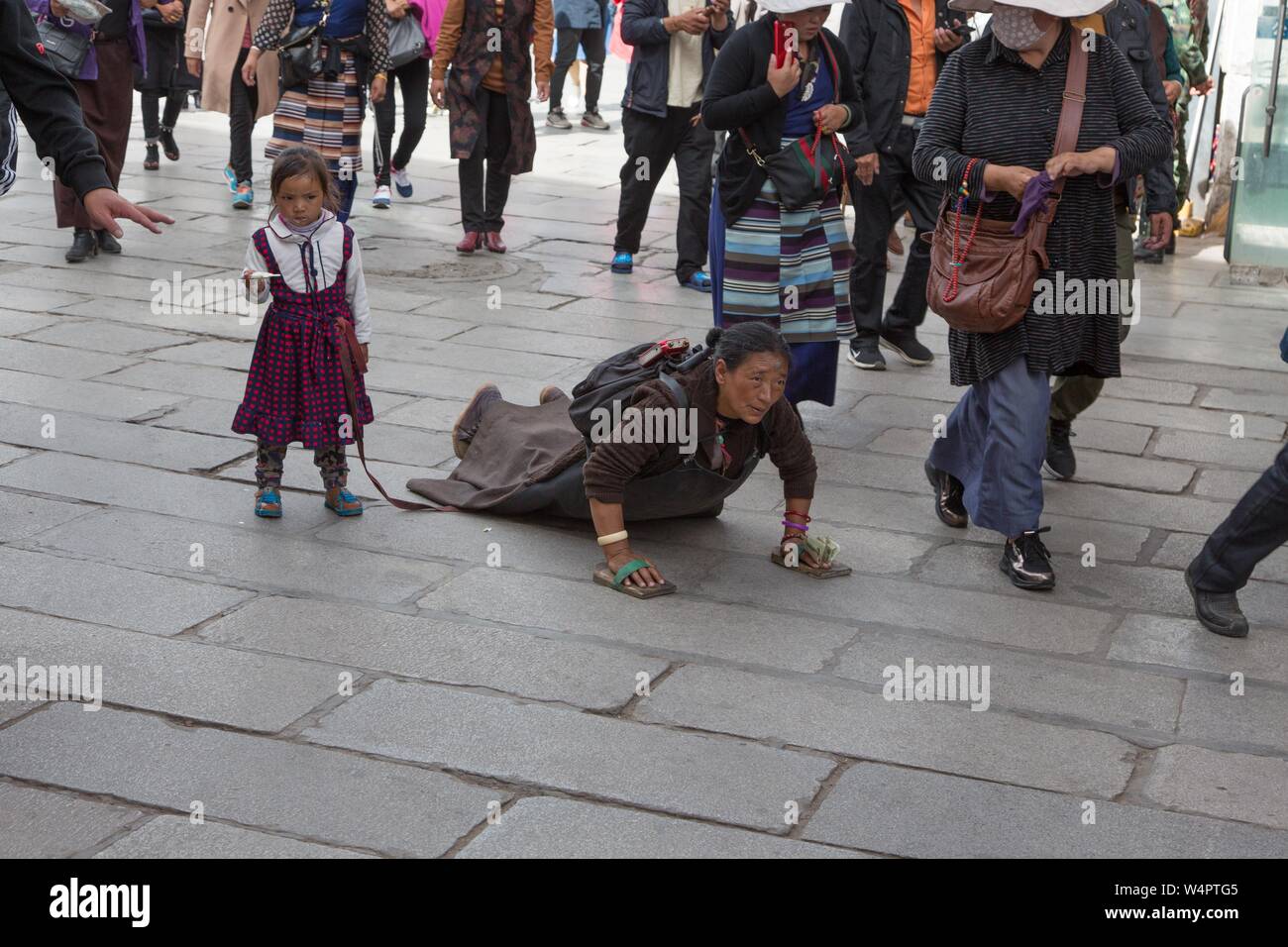 Ausführen einer Länge und dann niederwerfen, Pilger mit Kind Kreisen, den Jokhang Tempel in Lhasa, Tibet, China Stockfoto