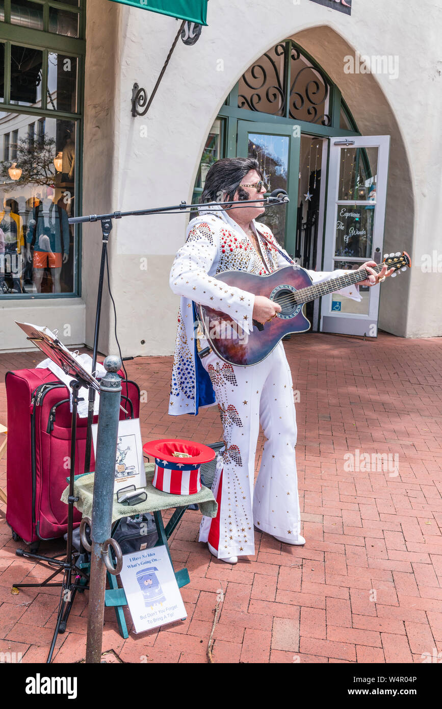 Ein Elvis Presley Imitator, in einer Elvis gekleidet wie weiß Pailletten Kostüm, spielt Gitarre und singt mit einem Mikrofon auf dem Bürgersteig vor Stockfoto Ein Elvis Presley Imitator, in einer Elvis gekleidet wie weiß Pailletten Kostüm, spielt Gitarre und singt mit einem Mikrofon auf dem Bürgersteig vor Stockfoto
