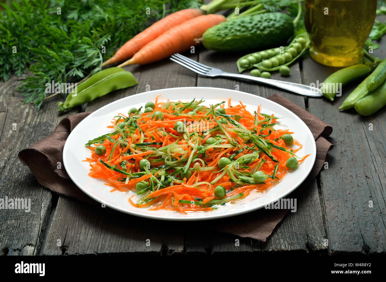 Hausgemachte Gemüse Salat mit Karotten, Gurken, Pinienkernen und grünen Erbsen auf weiße Platte Stockfoto