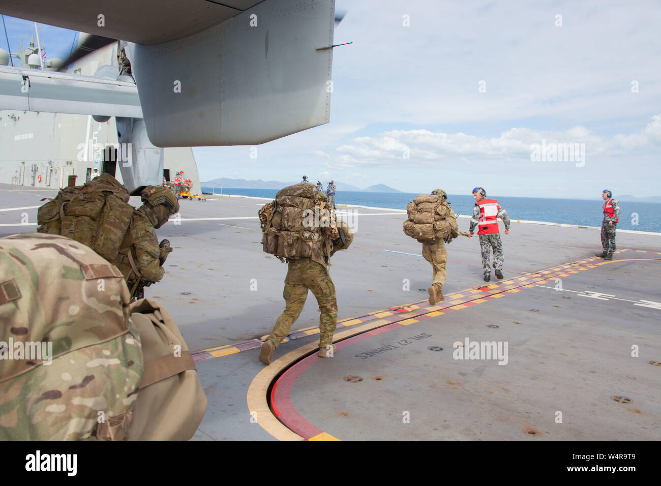 Australische Soldaten offload eine MV-22 B Osprey Kipprotor-flugzeug mit Marine Medium Tiltrotor Squadron 265 (verstärkt), 31 Marine Expeditionary Unit, an Bord der landing Helicopter dock HMAS Canberra (LO 2), Coral Sea, 23. Juli 2019. Die 31. MEU und USS Wasp (LHD 1) amphibische Bereit Gruppe beteiligen sich derzeit in der Übung Talisman Sabre 2019 vor der Küste im Norden von Australien. Talisman Sabre wurde entwickelt, um Partner Nation combat Readiness und Interoperabilität durch realistische, eine entsprechende Ausbildung zu verbessern, die Steigerung der Fähigkeit und Fertigkeit zu Krise als Teil einer kombinierten e reagieren. Stockfoto