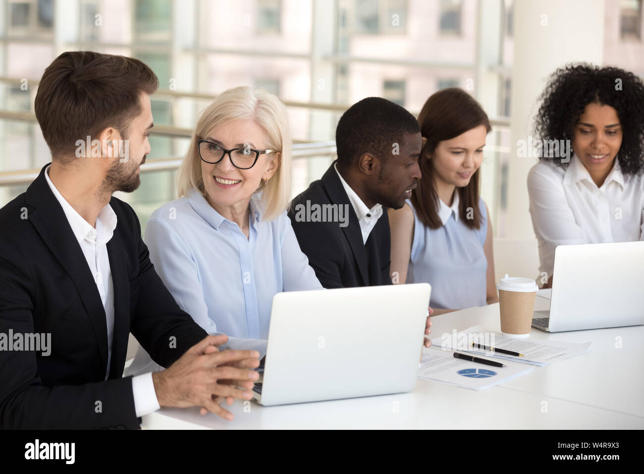 Lächelnd diverse Kollegen zusammen am Laptop arbeiten im Konferenzraum. Stockfoto