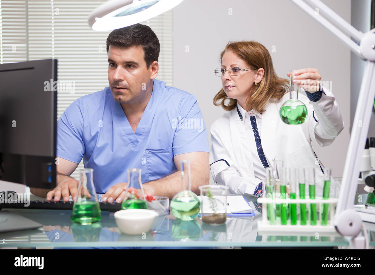 Führende Wissenschaftlerin mit Ihrer Assistentin Kontrolle der Daten für ihre wissenschaftliche Tests. Wissenschaftler in der Landwirtschaft. Stockfoto