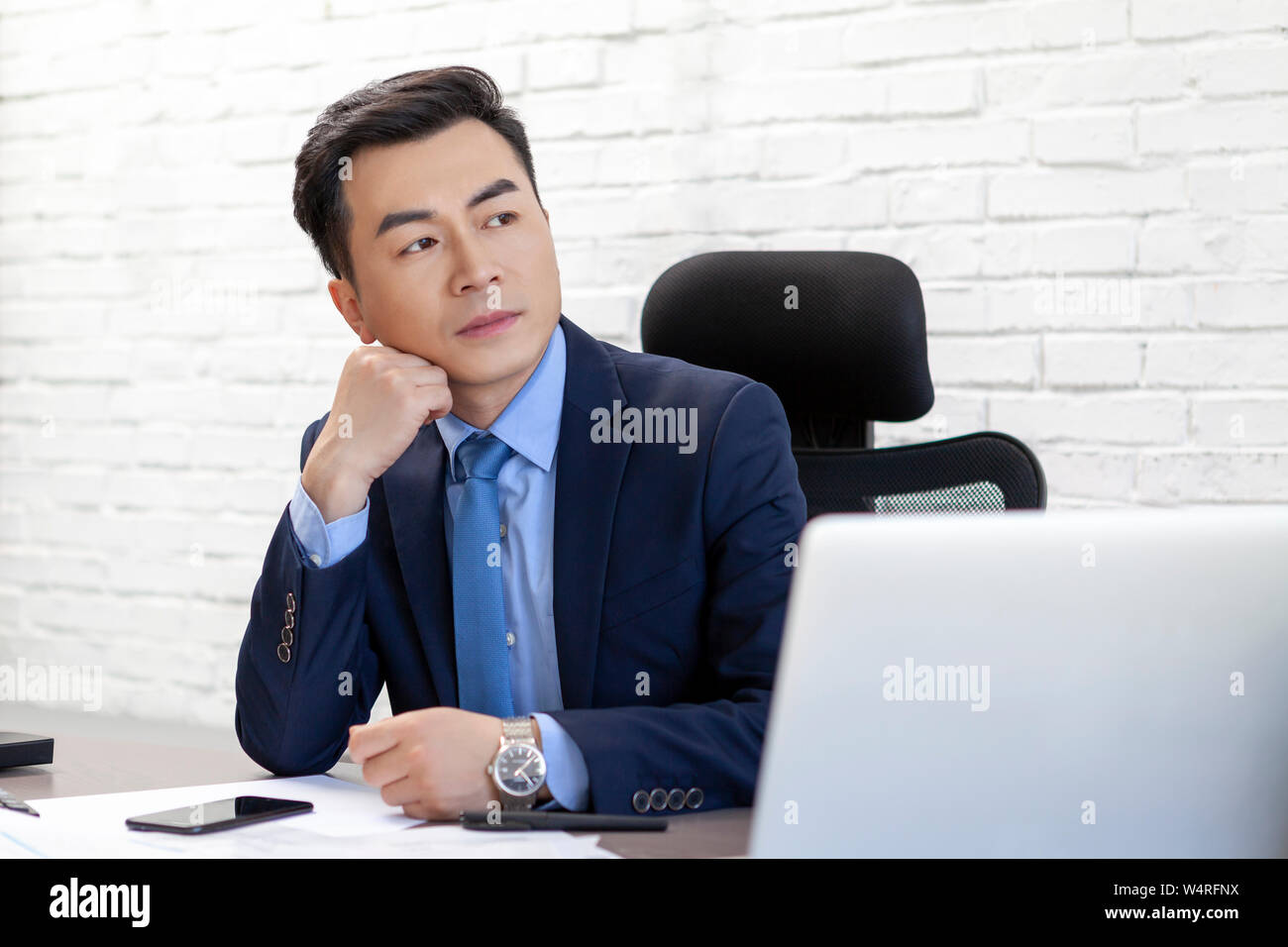 Mann im eleganten Anzug hinter dem Schreibtisch sitzen, Peking, China Stockfoto