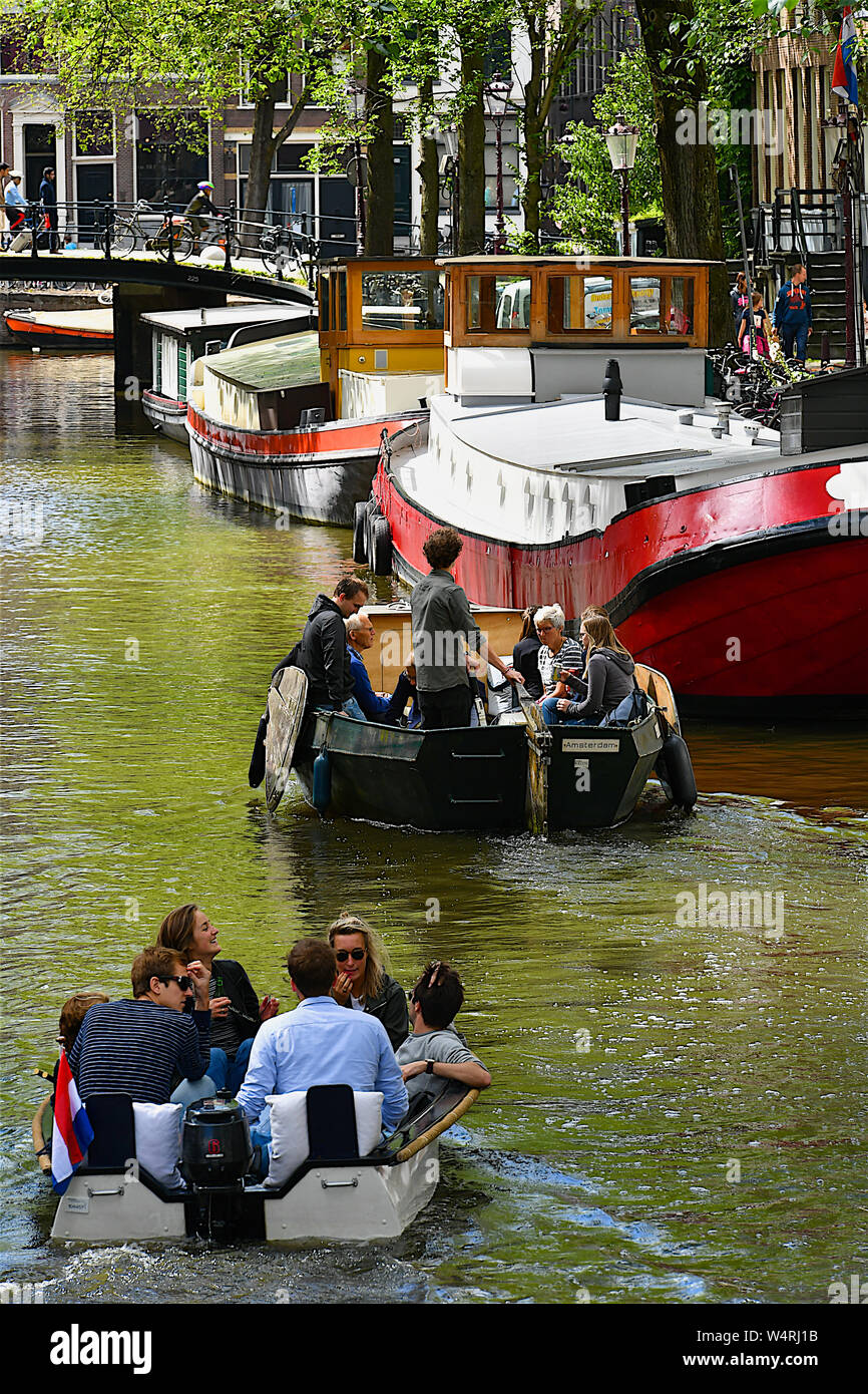 Menschen fahren Motorboote entlang Stadt Kanal, Amsterdam, Niederlande Stockfoto