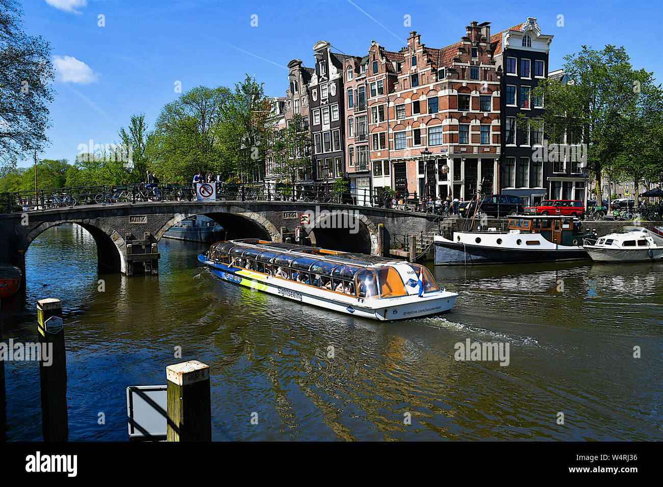 Tourboat vorbei unter Bogenbrücke, Amsterdam, Niederlande Stockfoto