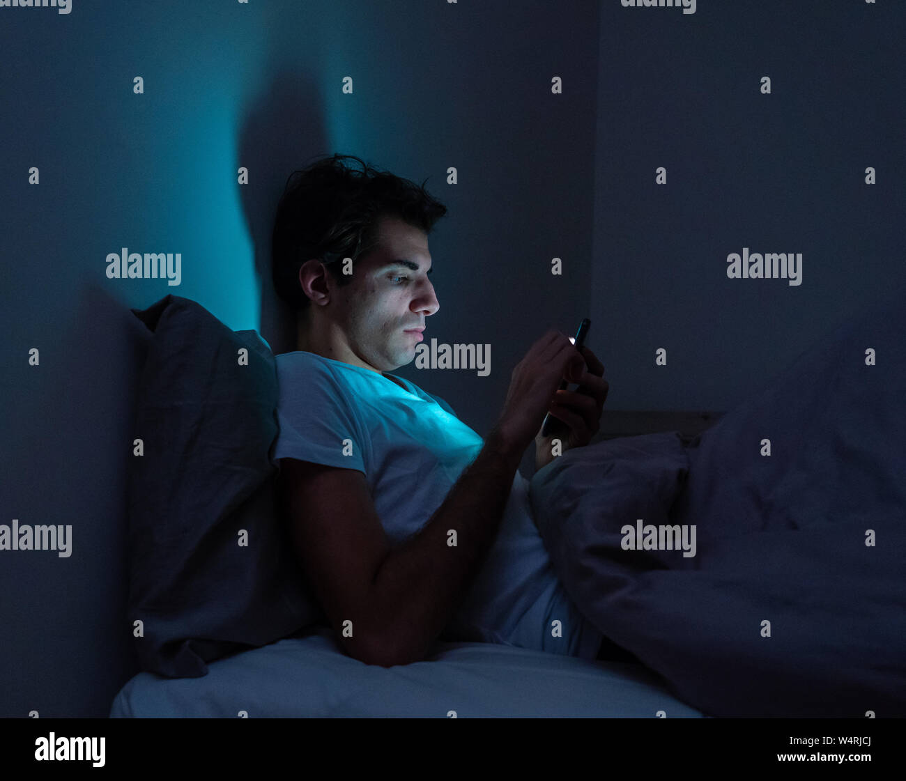 Lifestyle Portrait von Handy süchtiger Mensch wach bis spät in die Nacht im Bett mit smart phone Kontrolle mag und Anhänger, chatten, flirten, Dating auf s Stockfoto